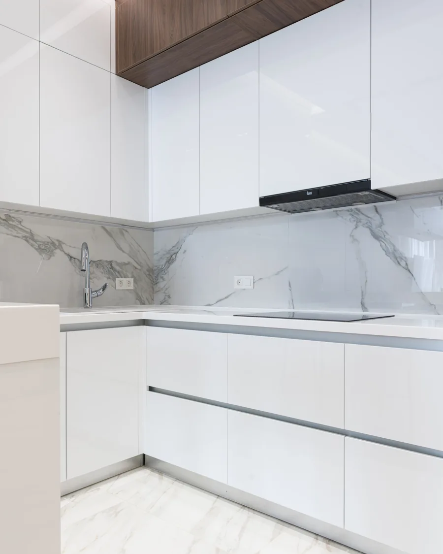 Layered pale kitchen materials including warm white cabinetry, light stone, tile and pale wood